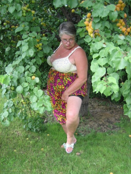 A fruit bearing tree is the habitat of Fat Granny Girdle Goddess, who displays her large tits.