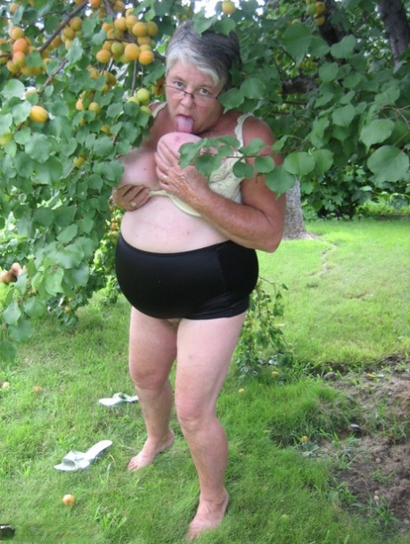 Fat granny Girdle Goddess exposes her large tits under a fruit bearing tree