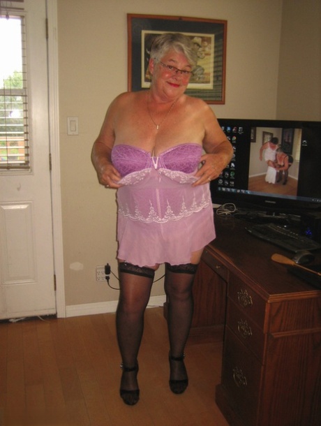 An elderly woman who is a Girdle Goddess exhibits her nude body in layers of lingerie and nylons.