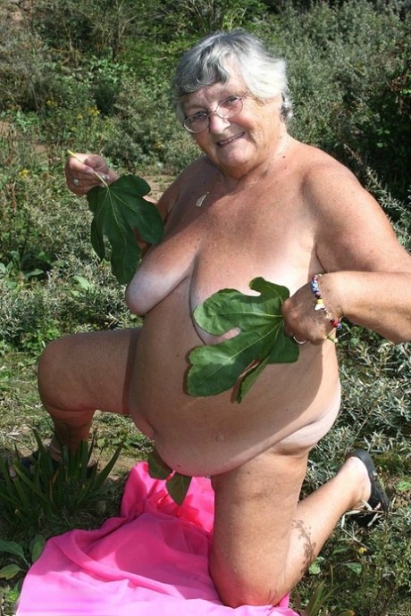 On dirty ground, Grandma Libby, a plump British woman, takes out her clothes and gets naked on a towel.