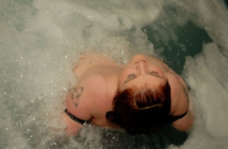 Unclothed and naked, a black individual named Black Widow (AK) enjoys themselves in a hot tub.