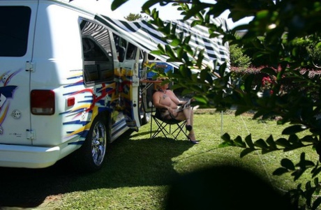 Mary Bitch, a mature blonde, displays her big tits and pussy outside a B class camper van.