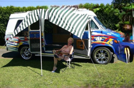 The image shows Mary Bitch, a mature blonde woman with big breasts and pussy outside a B class camper van.