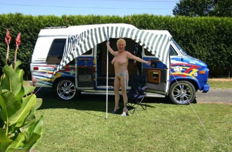 Young Mary Bitch, who is blonde at the age of 60 and has matured, displays her large tits and pussy outside a B class camper.