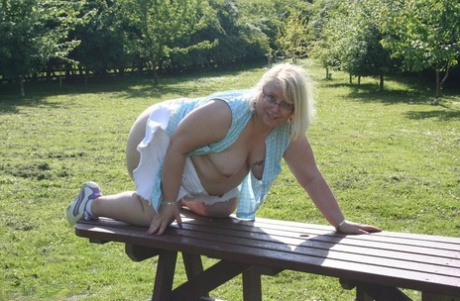 On a picnic table, Lexie Cummings, an elderly woman who is too old, places an orange in her pinky eye.