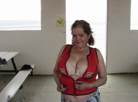 Misha MILF, an older redhead, exhibits her large tits by a lake before engaging in dildo swimming.