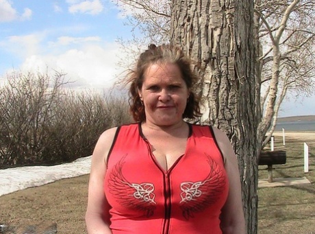 Big tits: Misha MILF, an older redhead, shows off her large tits by the lake before doing some riding with a dildo.