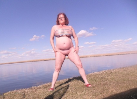 The large tits of Misha MILF, an older redhead who is also quite tall, are observed by the lake before she engages in dildo practice.