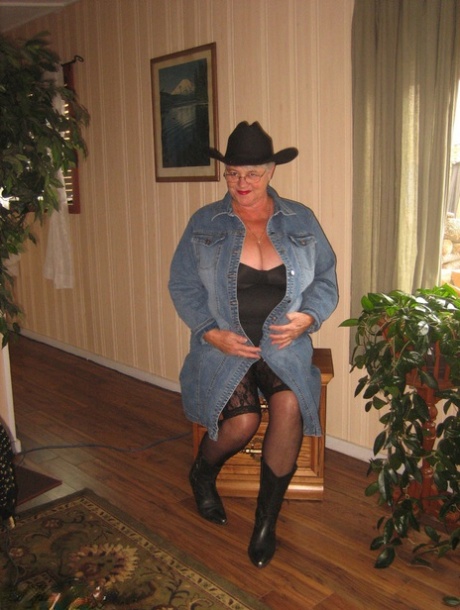 A cowgirl hat and boots are worn by Fat Oma Girdle Goddess, who is shown in a naked look.