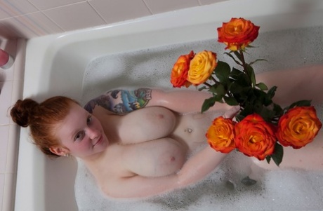 Kaycee Barnes, a pale redhead and exercise enthusiast, exhibits her sizable breasts and buttocks while bathing.