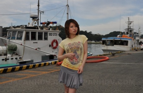 While wearing a skirt, Miki Uemura, the young girl from Japan, poses on an abandoned dock.