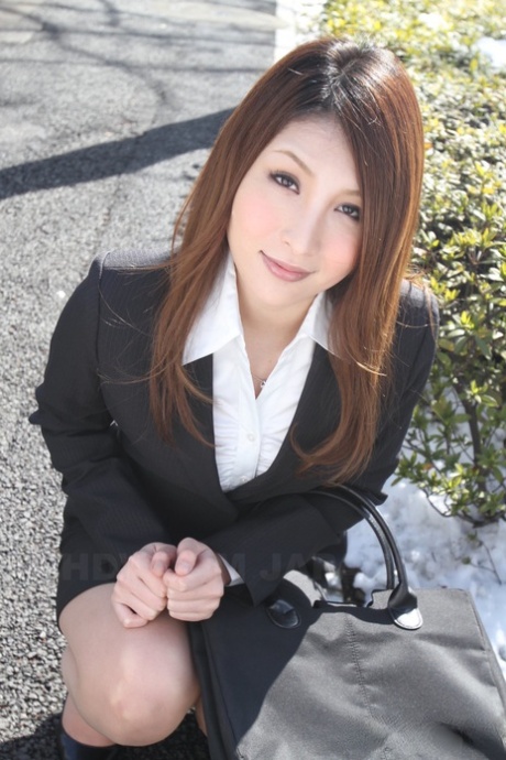 An attractive Japanese girl in a suit shows off her beautiful face with hot red hair.