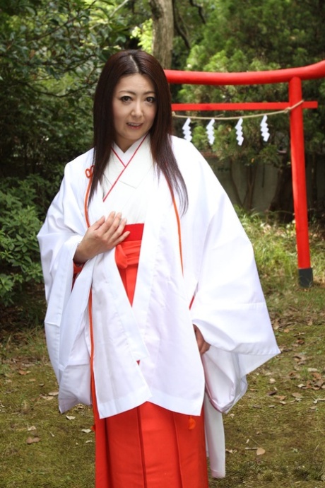 Out in the yard, older Japanese woman Ayano Murasaki displays her tits and bush.