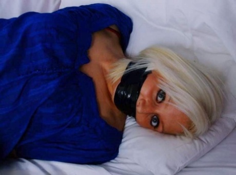 On her bed, the platinum blonde is restrained and kept in silence with duct tape.