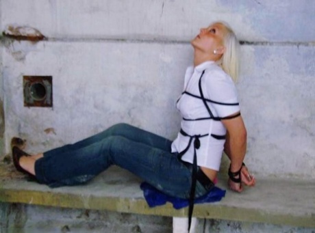 In blue jeans and a white shirt, a British woman is tied up and gagged.