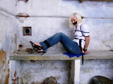 Blue jeans and a white shirt are worn by a British woman who is tied up and gagged.