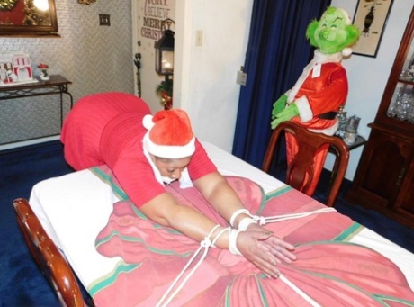 Ebony fatty is draped over a table at Christmas, with her underwear visible.