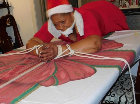 Ebony fatty is tied over a table at Christmas with her underwear showing