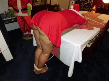 Ebony fatty is tied over a table at Christmas with her underwear showing