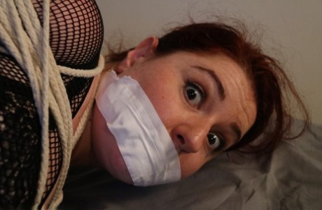 Redheaded Fatty Is Silenced With Medical Tape While Tied Up With Rope On A Bed