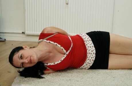 In her attire, a dark-haired woman is seen covered in black clothing on a carpet.