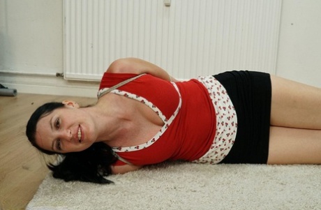 A woman with dark hair is draped over her clothes on a carpet.