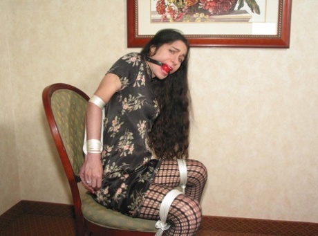 A girl with long, brunette hair is spotted and shows her pussy while being restrained and gagged.