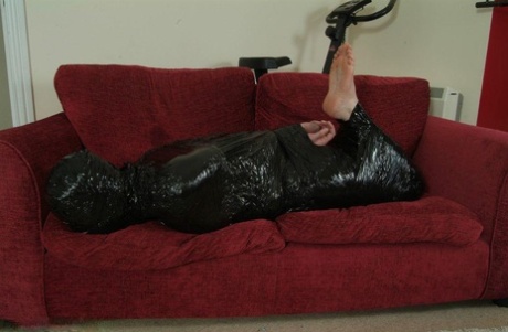 Ball gagged, white female is hogtied and placed in garbage bags.