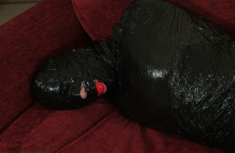 Ball gagged, white female is hogtied and placed in garbage bags.