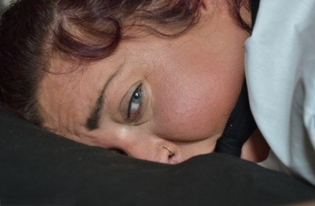 Толстая женщина связана на четвереньках лицом вниз на кровати с кляпом во рту