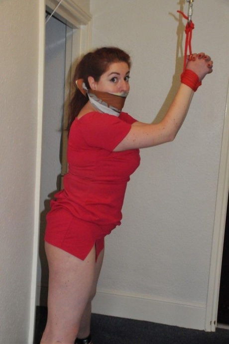 Confined and gagged, the fully clothed female reveals her large ass while being restrained.