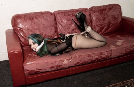 A white girl with dyed hair finds herself on a Chesterfield, gagged and tied up.