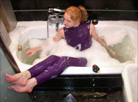 A white girl bares her feet while bathing in purple latex clothing.
