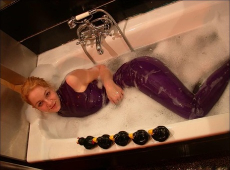 The white girl exposes her bare feet while bathing in purple latex clothing.