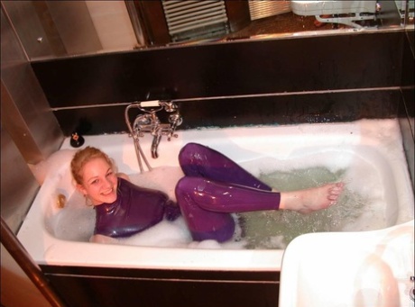 White girl wears purple latex and she shows her bare feet in the bath.