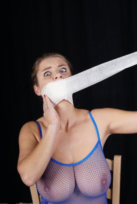 Blindfolded and gagged, the girl is tied to a chair in see-through clothing.