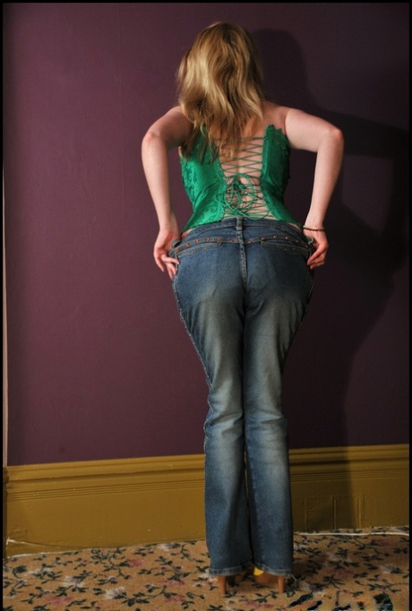Tiny older woman Tasty Trixie displays her bustier figures in blue jeans and a bouffant top.