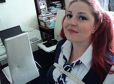 The schoolgirl with red hair and weight is tying herself to a chair while being gagged with her cleaved legs.