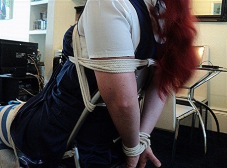 Tied down on a chair: A schoolgirl with red hair and fat body is seen here wearing only her hands while being tied up with her legs in her cleave.