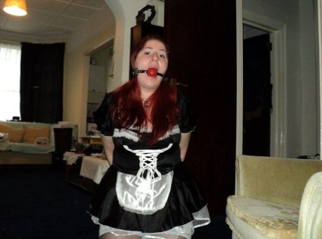 At work, a fat maid with red hair is being ballgged and given handcuffs.