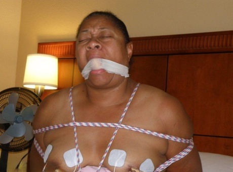 A bed-bound ebony fat gets electrically shocked while being gagged and tied up.