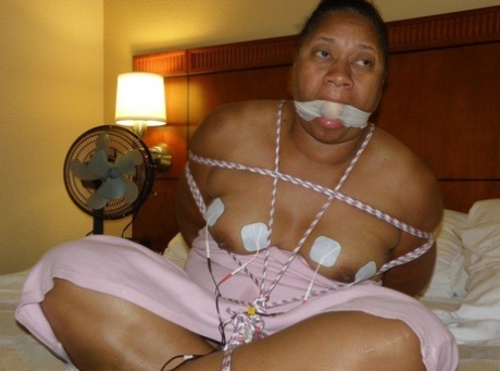 Electrical shocks are experienced by ebony fatty while being restrained on a bed.