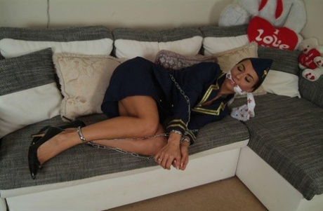 The hot stewardess is left in her uniform on a sofa, restrained and gagged.