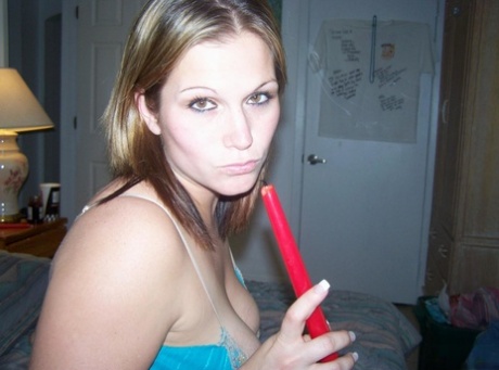 Toni, a horny MILF, places a lit candle in her anus upon a bed.