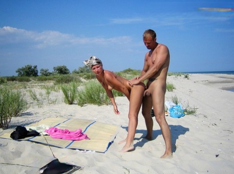 A blonde girl and her boyfriend have sex in the sun on a deserted sandy beach.