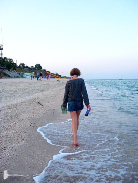 A female who is an amateur and has red hair switches to bikini before going for a swim in the ocean.