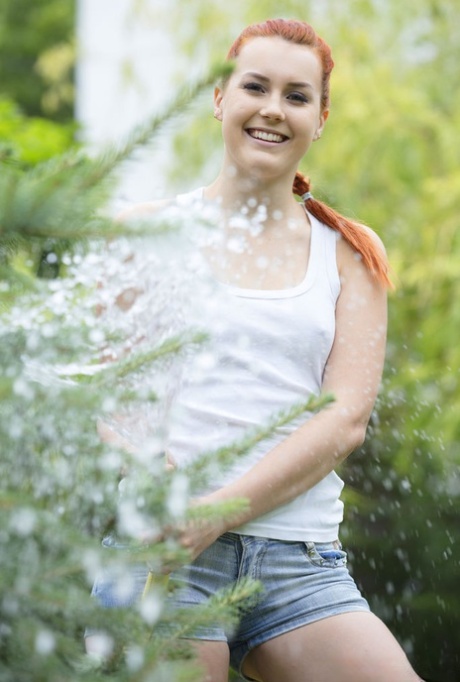 Before giving herself a finger lift, Charli Red, a fair-skinned redhead who has pretty hair, wets herself with a hose.