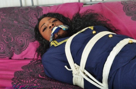 An Ebony stewardess finds herself in her uniform tied up and gagged on a bed.