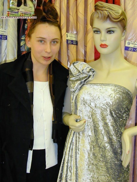 Young-looking girl shows her fists next to a mannequin after using the toilet with some water.