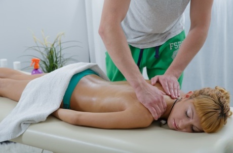 Young redhead receives massage from her massage attendant during a rub down.